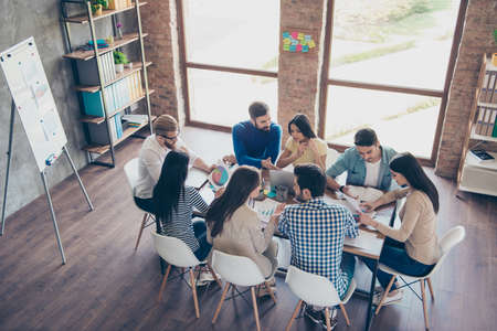 Top view of partners  in casual clothes. They are focused, discussing the ideas for new start-up at nice comfortable  officeの写真素材