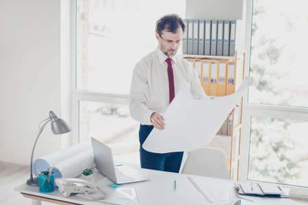 Concentrated specialist is holding  scheme and looking at the project. He is focused on ideas