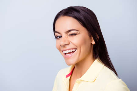 Successful smiling latino mulatto girl is winking on light blue background. She has a beaming smile!