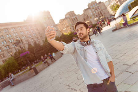 Selfie time! Young funky blogger is making photo for his social networks page, he is posing in a...