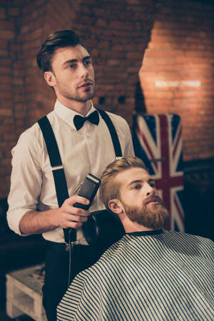 Styling for a handsome young guy. Barber shop hairdresser is attractive and wearing classic outfit, he is focused and seriousの写真素材