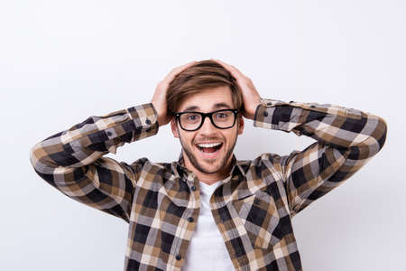 Shocked young bearded student is holding his head. He is in a casual outfit on pure background, amazedの写真素材