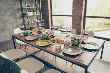 Generously served wooden table with yummy fresh  dishes and glasses of red wine are ready for the...