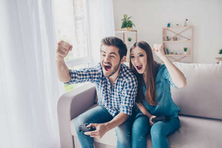 Married young people are fans of video games, love spending their weekend at home together. They are screaming and gesturingの写真素材