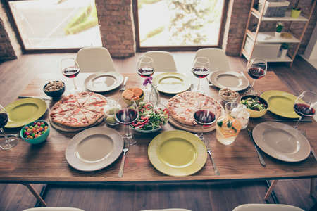 Nicely served wooden table with tasty amazing dishes and glasses of red wine are ready for dear guestsの写真素材