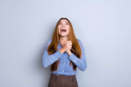 A dream of the young cute entrepreneur came true. She is very excited, wearing smart outfit, standing on pure blue backgroundの写真素材