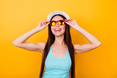 Happy young asian girl on summer vacation. She is in a stylish hat, trendy sun glasses, wearing...
