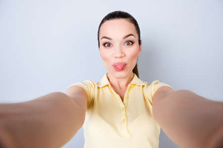 Attractive young hispanic teen is making a selfie on the camera and has tongue out, fooling around