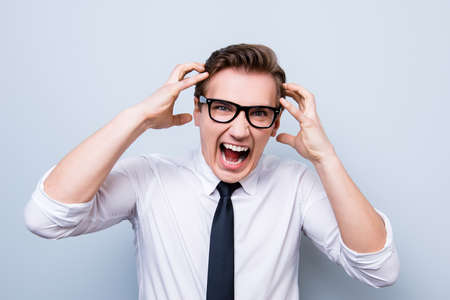 Going crazy and insane. Close up portrait of shouting stressed young entrepreneur in a formal wear...