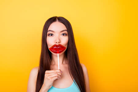 Young asian, wishing to have something lips like a lolipop she is holding, she stands in summer...