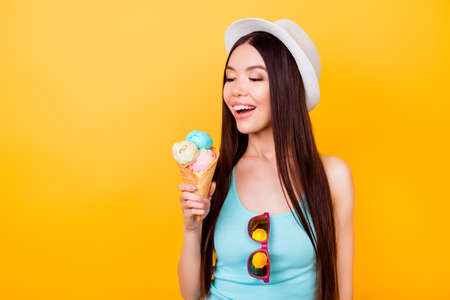 Cheerful young korean lady looks at tasty ice cream of three scoops of different flavors, going to...