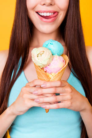 Close up cropped photo of tasty ice cream of three scoops of different flavors, girl is holding it,...