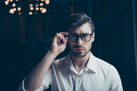 close up of successful young guy with bristle in classy shirt, adjusting trendy glasses. so stylish and stunningの写真素材
