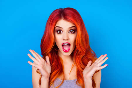 Young shocked  foxy with wide open eyes and mouth is gesturing wonderment with palms of hands, on the blue backgroundの写真素材