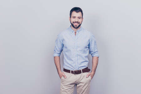 Success concept. Stylish young smiling bearded brunet is standing on pure gray background.の写真素材