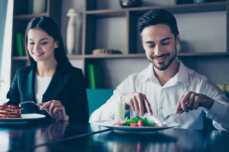 Two young cute lovers are sitting in a fancy restaurant, wearing smart outfits and eating delicious...