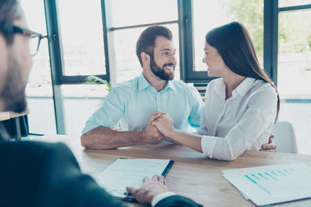 Excited married couple, having consultation with a lawyer in his office, about to sign a contract for buying purchase, all are dressed in formal outfits, smilingの写真素材