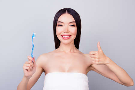 Dental health concept. Gorgeous asian girl in white towel is smiling, on light background, she has a beaming smileの写真素材