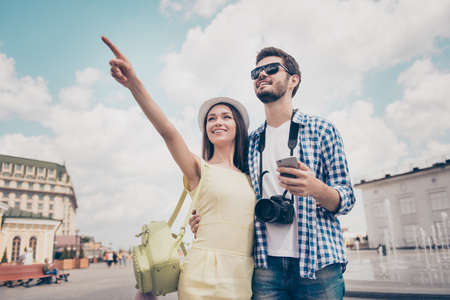 Check this out! Happy young couple of tourists are on vacation, in casual outfits, cap, eyewear and...