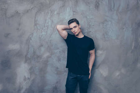 Portrait of handsome stylish man in casual clothes posing and touching his neck against gray backgroundの写真素材