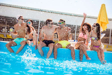 Six multi national tourists are enjoying at the pool sunny beach disco, with drinks.の写真素材