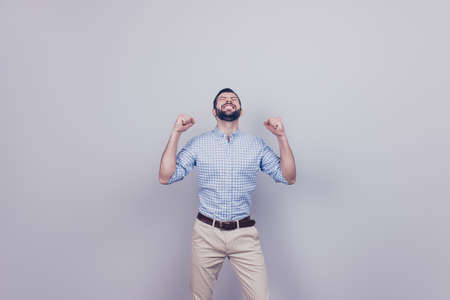 A dream of the young bearded brunet entrepreneur came true. He is very excited, wearing smart outfit, celebrating, stands on pure backgroundの写真素材