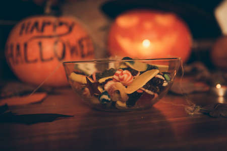 Close up focus shot of a transparent bowl with many diverse colorful tasy yummies - sugar lolipops,...