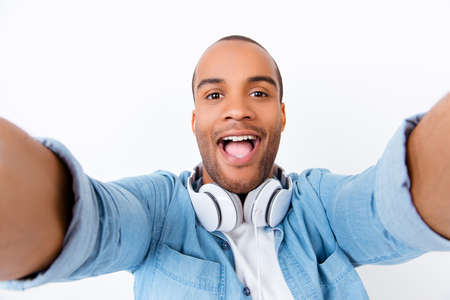 Funky swag selfie! Young african teen hipster is taking selfie shot on pure white backgound, amazed,...