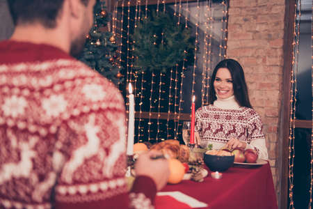 Close up cropped shot of back of a guy, festive friends sitting at x mas fest, in knitted cute traditional x mas costumes with ornament, enjoy, garlands, night, sparkles, true feelingsの写真素材
