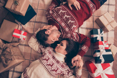 Dreamy adorable sweet cute friends cuddling on the floor on beige checkered blanket, so romantic, winter feast at coziness, red and green surprises, with whitenribbonsの写真素材