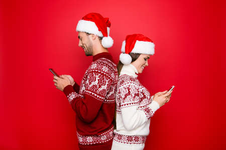 Addiction, chat, communication, digital, happiness in internet, december, winter time. Married lovers are browsing, typing, reading at their pda, standing back to back, wearing noel costumesの写真素材