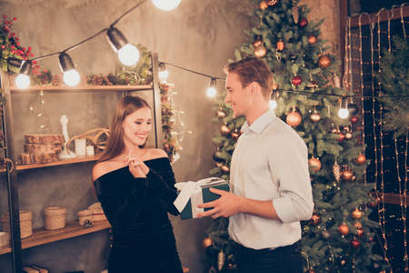 Sweet brown haired husband and cute wife are receiving green gift with white ribbon, so excited, cheerful, elegant, traditional decorations, x mas, enjoy, winter, december festive magic noel time!の写真素材
