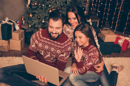 Modern networking, communication, online web wireless telecommunication, roaming connection, chat convrsation, distance. Three relatives in x mas costumes, at home, wave with hand palmsの写真素材