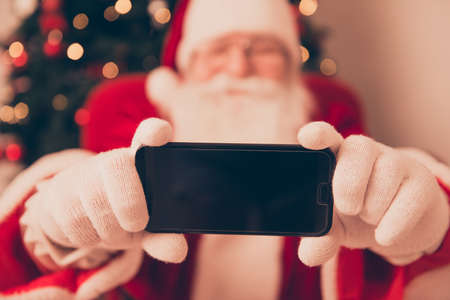 Close up blurred view of Saint Nicholas photographer in red traditional coat and head wear, taking shot on camera, indoors, making holly jolly x mas noel festive memoriesの写真素材