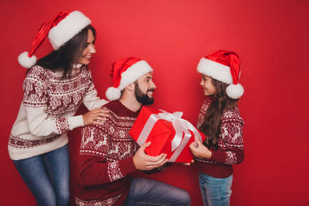 Side profile view of three cheerful excited beautiful relatives, married couple, small girl, hold...
