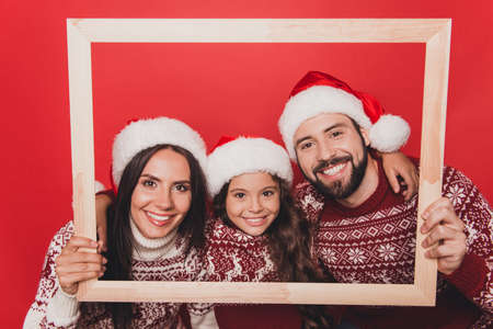 Adorable caucasian couple with small sweet cute girl bonding, so excited in knitted cute traditional x mas costumes with ornament, head wear, december, noel time, hold frameの写真素材