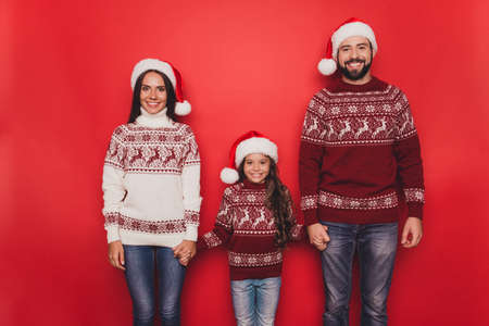 Three excited relatives, married couple, mom and dad, small adorable cute sweet girl with curly brown hairstyle, in knitted cute traditional costumes, x mas noel timeの写真素材