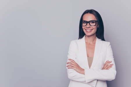 Close up portrait of caucasian gorgeous stunning charming lovely cute expert business lady, standing on pure light grey background, grinning, in black cool specs, with crossed armsの写真素材