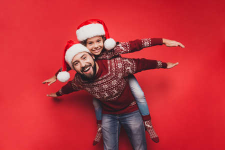 Handsome dad with small adorable sweet cute girl fooling around, excited in knitted cute traditional x mas costumes with ornament, head wear, december, noel time, freedom, celebrate, winterの写真素材