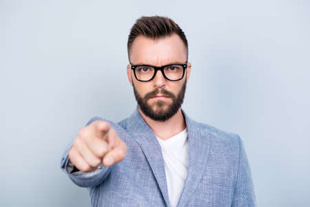 You! Strict handsome bearded brunet man is choosing you, pointing at the screen, wearing formal outfit, on a pure light background, harsh and severeの写真素材