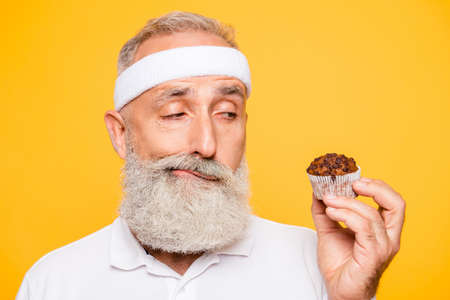 Athlete cool uncertain unsure ponder fit picky grandpa holds forbidden tasty yummy treat, decides. Weightloss, healthcare, restriction, question, thoughts, workout, gym, regime, bodycareの写真素材