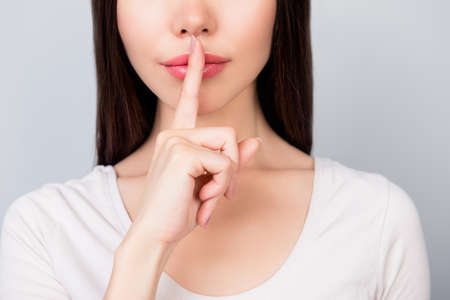 Shhh! Close up portrait of half face of young woman with  finger showing hush silence sign, gesture...