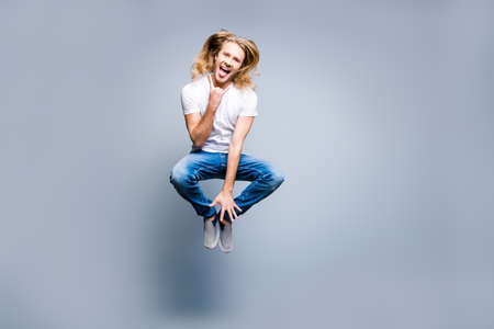 The best weekend I have ever had! Joyful, amazed, crazy music lover in casual clothes is jumping up because he visited a rock and roll concert, isolated on grey backgroundの写真素材