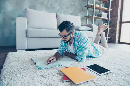 Portrait of student in casual outfit  preparing for lessons, doing homework while lying on the floor at homeの写真素材