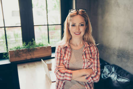 Portrait of young happy, blonde woman with beaming smile after work standing in her work place with...