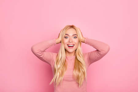 Happy excited young astonished surprised lovely pretty woman in pink clothes. She is touching her head because she can't believe her eyes looking at sales, isolated on vivid pink backgroundの写真素材