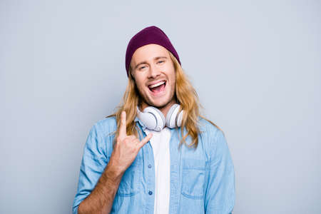 Stylish cool joyful guy with long blonde hair is dressed in denim jeans clothes, is listening to...