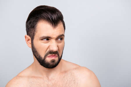 Close up portrait of emotional man with dislike emotion on his face, looking to the side, standing over grey backgroundの写真素材