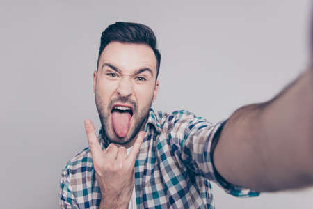 Self portrait of  attractive, crazy man with bristle, stubble, shooting selfiye and showing rock and...