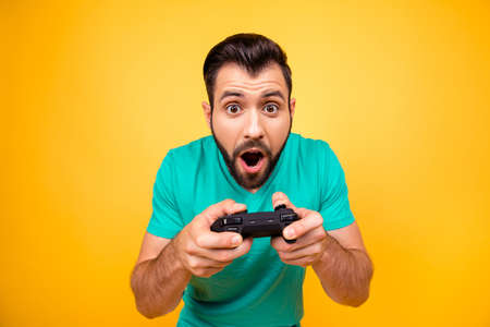 Close up portrait of funny joyful cheerful happy guy, he is rejoicing his victory with gamepad in hands, isolated on bright yellow backgroundの写真素材